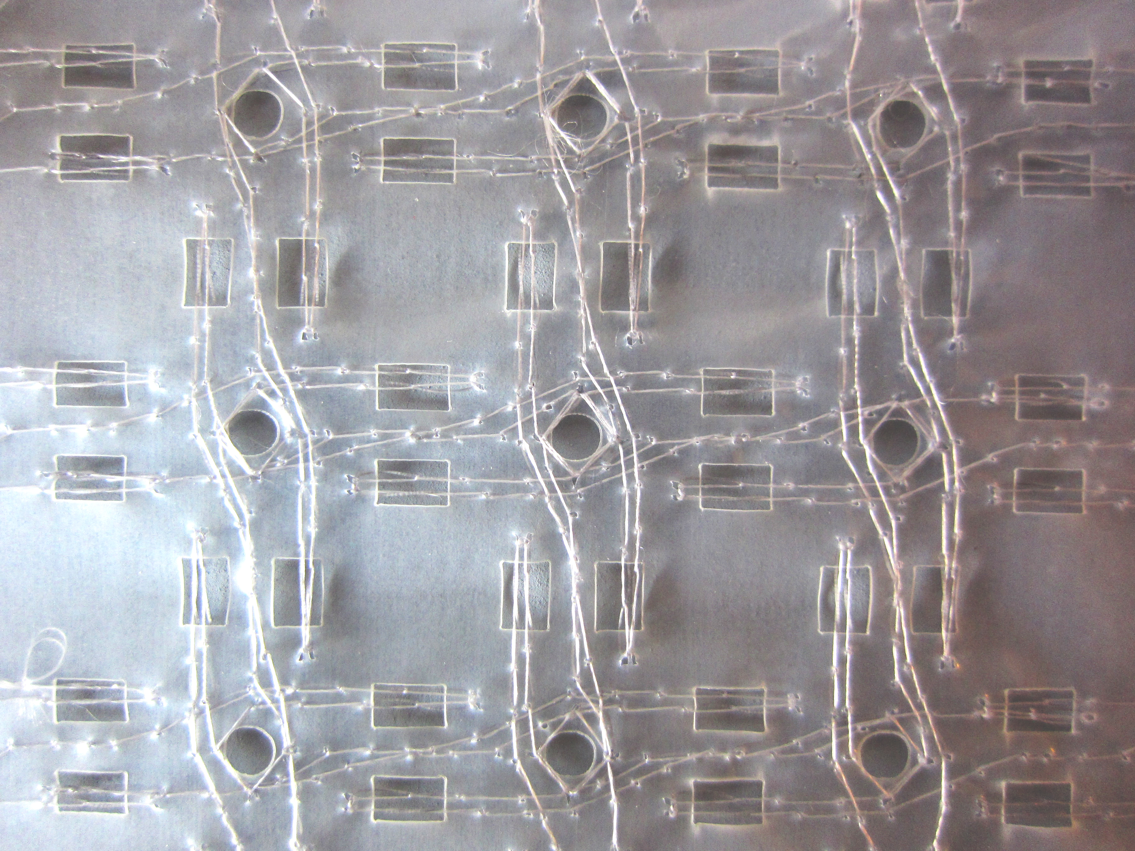 Fishing line sewn in a pattern around cutouts in a water-soluble clear plastic sheet